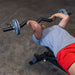 Male athlete performing a tricep skull crusher with the Body-Solid FAT CURL BAR OB48F, demonstrating the bar's thick 2" grip and effectiveness in targeting the triceps during strength training.