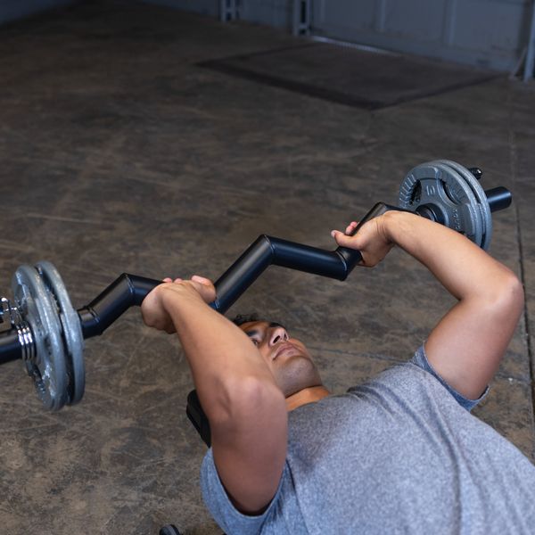 Close-up of a male athlete performing a tricep skull crusher with the Body-Solid FAT CURL BAR OB48F, highlighting the thick 2" grip and focused tricep engagement during the exercise.