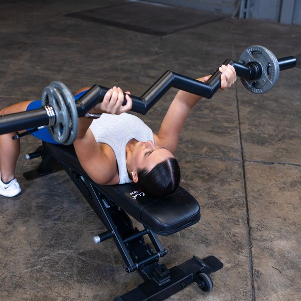 Close-up of a female athlete performing a lying tricep extension with the Body-Solid FAT CURL BAR OB48F, highlighting the thick 2" grip and focused tricep engagement during the exercise.