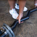 Close-up of a male athlete bending down to grab the Body-Solid FAT CURL BAR OB48F, emphasizing the thick 2" grip and readiness for an intense bicep workout.