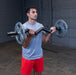 Close-up of a male athlete performing a standing EZ curl with the Body-Solid FAT CURL BAR OB48F, showcasing the thick 2" grip and intense bicep engagement during the exercise.
