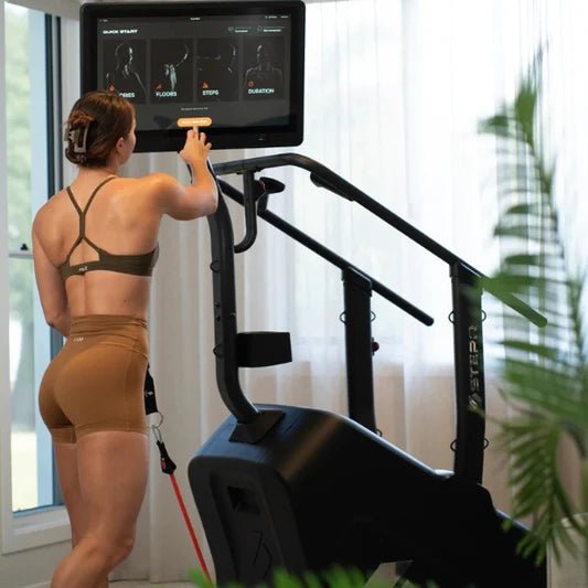Female athlete next to the STEPR+ Stair Climber using the swivel display to prepare for off-machine exercises, demonstrating versatility and workout options.