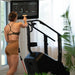 Female athlete next to the STEPR+ Stair Climber using the swivel display to prepare for off-machine exercises, demonstrating versatility and workout options.