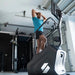 Male athlete working out on the STEPR+ Stair Climber, viewed from the floor looking up, emphasizing the compact design and 27” HD touchscreen.