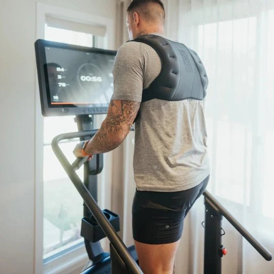 Male athlete working out on the STEPR+ Stair Climber at home, backside view, showing the compact design fitting easily into a residential space.