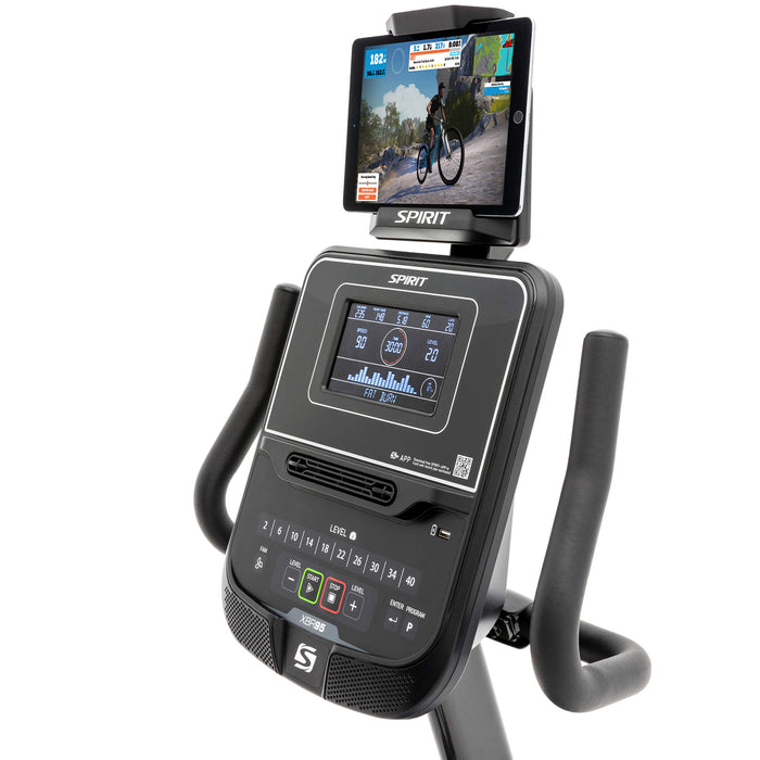 Close-up view of the Spirit Fitness XBR95 Recumbent Bike console with a tablet attached to the swivel-tilt tablet holder, showing workout data on the 7.5” multi-color ClearView™ display."