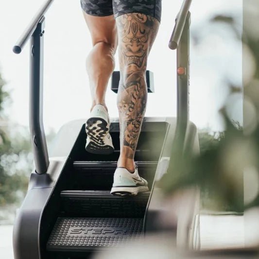 Close-up front view of the stairs on the STEPR+ Stair Climber with an athlete using the machine, highlighting the floating step design and foot placement.