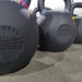 Close-up of heavy ISF kettlebells on the warehouse floor, viewed from the left side looking right.